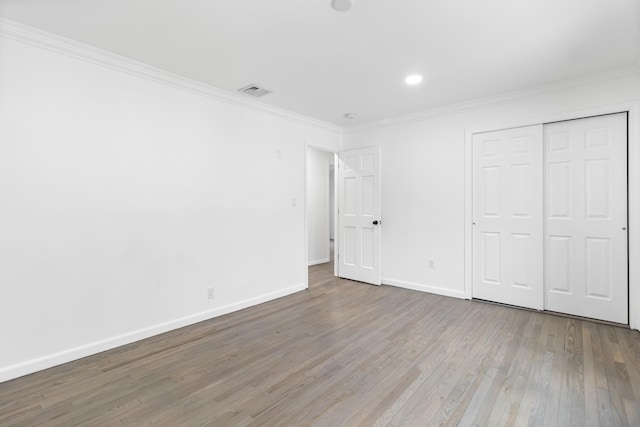 unfurnished bedroom with ornamental molding, a closet, wood finished floors, and baseboards