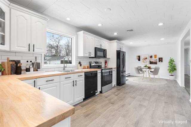 kitchen with wood counters, glass insert cabinets, black appliances, white cabinetry, and a sink