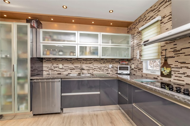 bar featuring light wood finished floors, stainless steel dishwasher, backsplash, and a sink