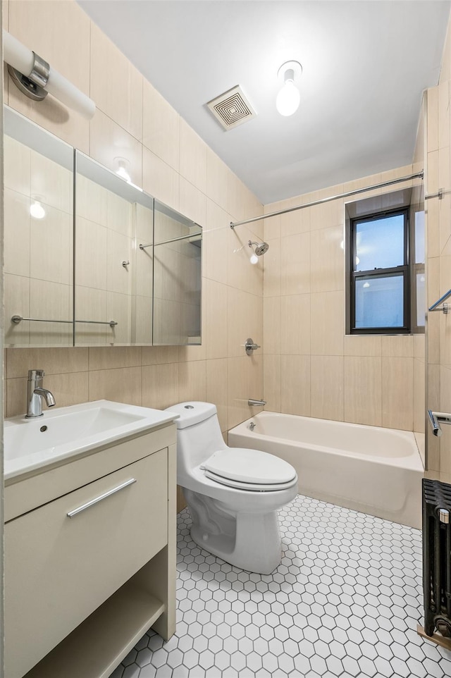 full bathroom with tile walls, tile patterned flooring, vanity, toilet, and tiled shower / bath