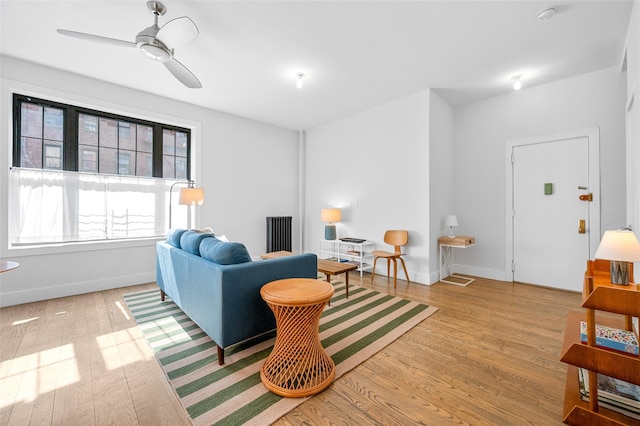 living room with a ceiling fan, baseboards, and wood finished floors