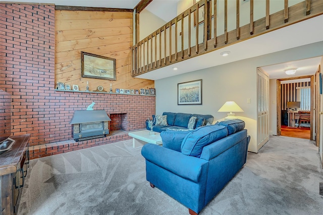 carpeted living room with a towering ceiling, brick wall, wood walls, and a wood stove