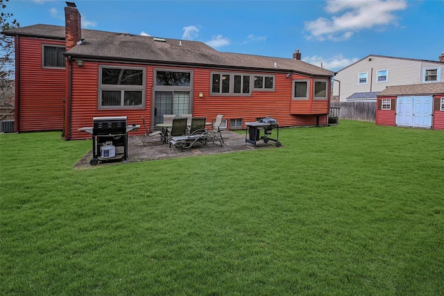 rear view of house with a storage shed, a lawn, and a patio area