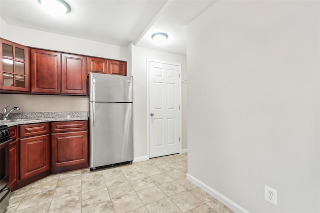 kitchen featuring light stone counters, appliances with stainless steel finishes, light tile patterned flooring, and sink