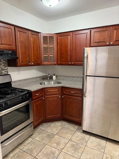 kitchen with sink, stainless steel appliances, light stone counters, extractor fan, and light tile patterned flooring