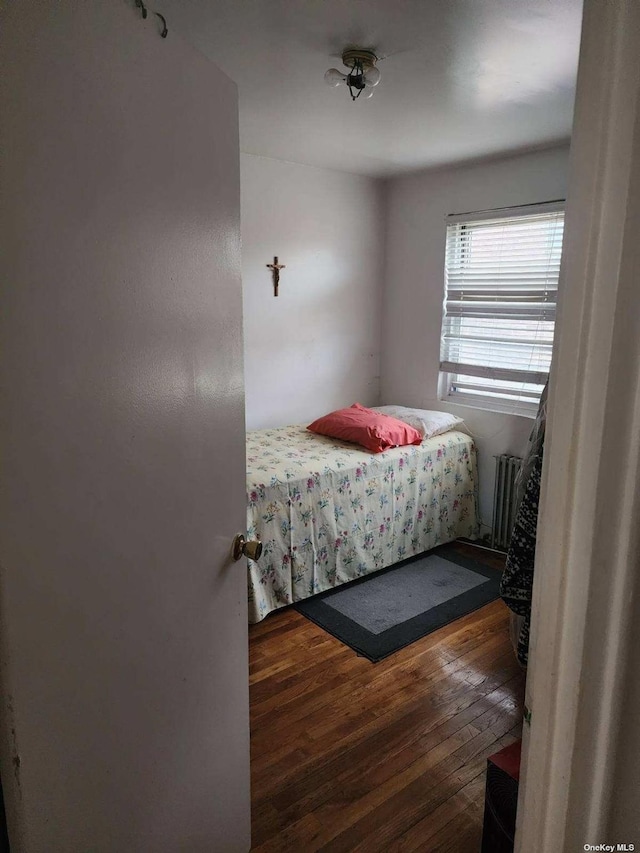 bedroom with radiator and dark wood-style flooring