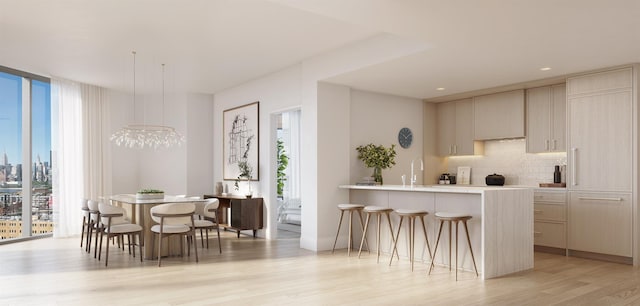 interior space featuring pendant lighting, sink, a wall of windows, decorative backsplash, and light hardwood / wood-style floors