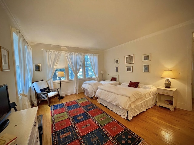 bedroom featuring ornamental molding and light wood-type flooring