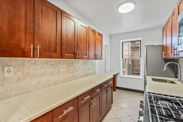 kitchen with light stone counters, light tile patterned flooring, sink, and decorative backsplash