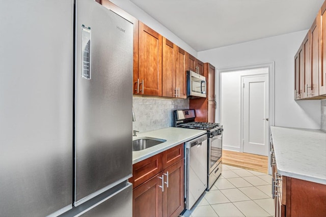 kitchen featuring tasteful backsplash, appliances with stainless steel finishes, sink, and light tile patterned floors