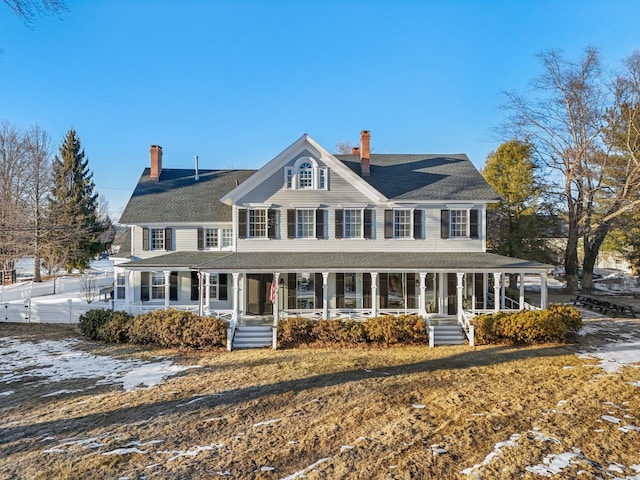 view of front of house with covered porch, a chimney, and fence