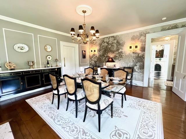 dining room with ornamental molding, dark wood-type flooring, a chandelier, baseboards, and wallpapered walls