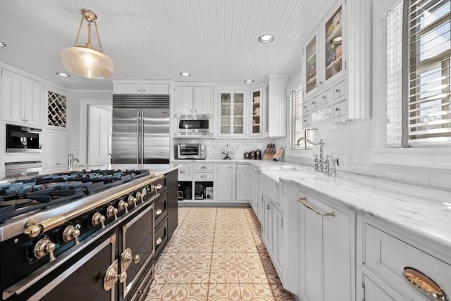 kitchen featuring built in appliances, light tile patterned floors, white cabinetry, and tasteful backsplash