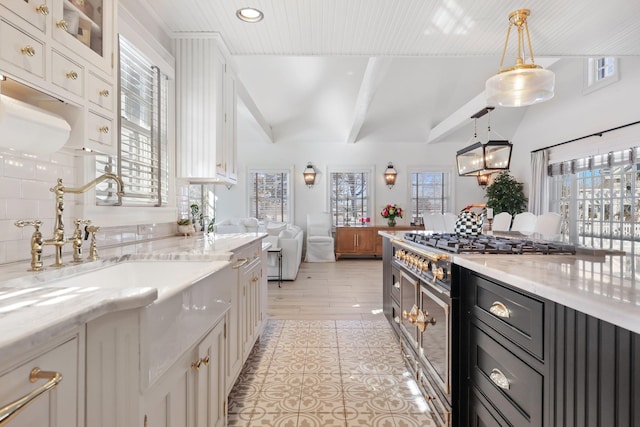 kitchen featuring visible vents, white cabinets, glass insert cabinets, high end stainless steel range oven, and a sink