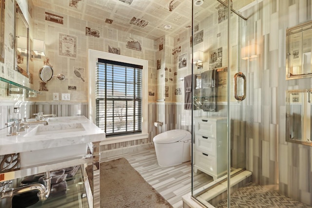 bathroom featuring toilet, a stall shower, a sink, and a wainscoted wall