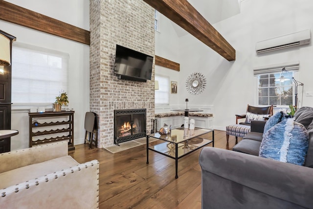 living area with beam ceiling, a fireplace, a high ceiling, a wall mounted air conditioner, and hardwood / wood-style flooring