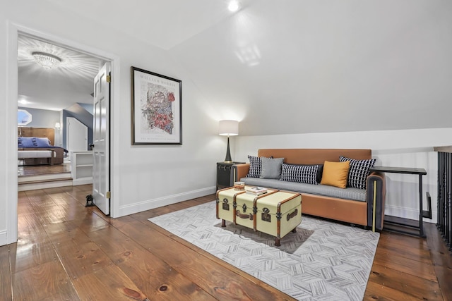 living area featuring lofted ceiling, hardwood / wood-style floors, and baseboards