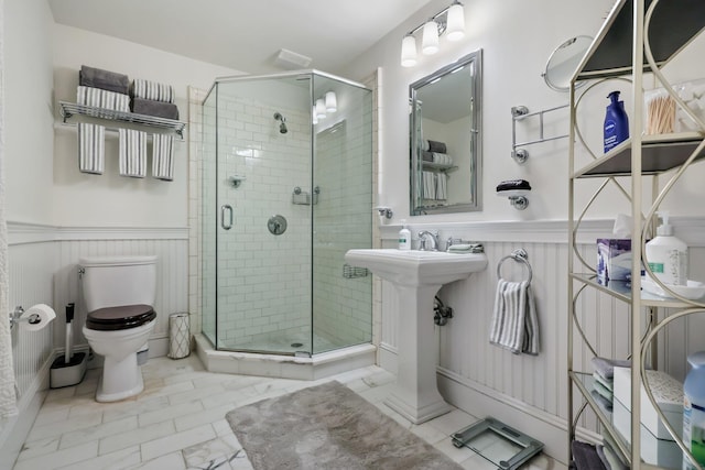 full bath featuring wainscoting, a sink, a shower stall, and toilet