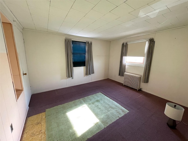 empty room with carpet floors and radiator heating unit