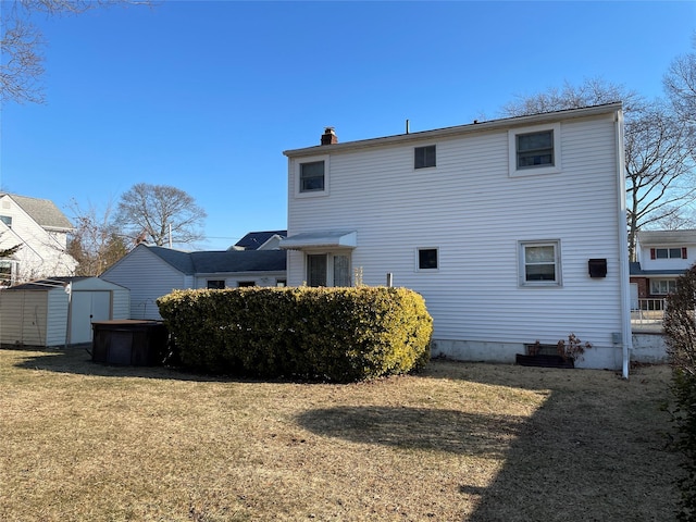 back of house featuring a storage shed, a lawn, an outdoor structure, and a chimney