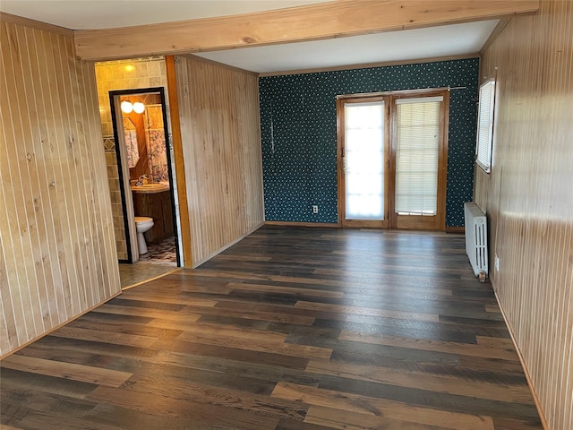 unfurnished room with radiator, beamed ceiling, dark wood-style flooring, and french doors