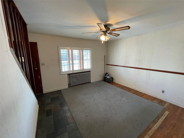 interior space with a ceiling fan and radiator heating unit