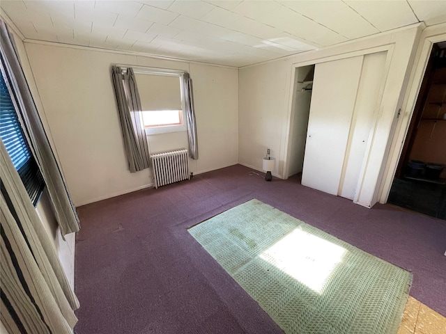 unfurnished bedroom featuring carpet floors, a closet, and radiator heating unit