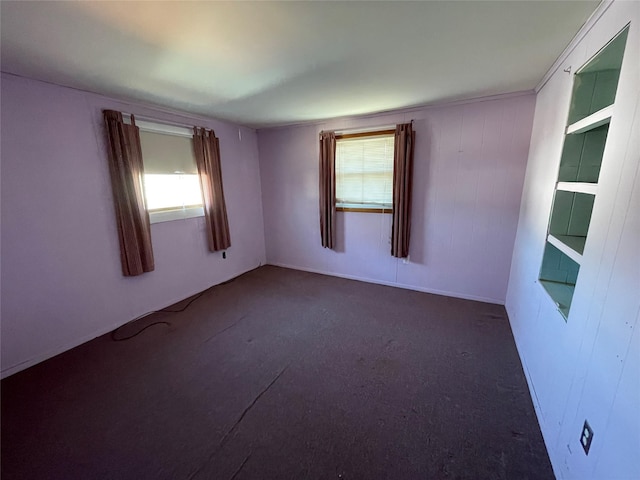 unfurnished room featuring dark colored carpet and a healthy amount of sunlight