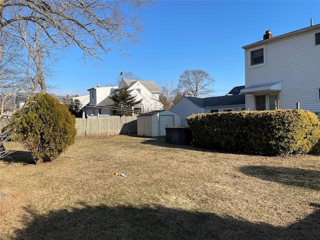 view of yard featuring an outdoor structure, fence, and a shed