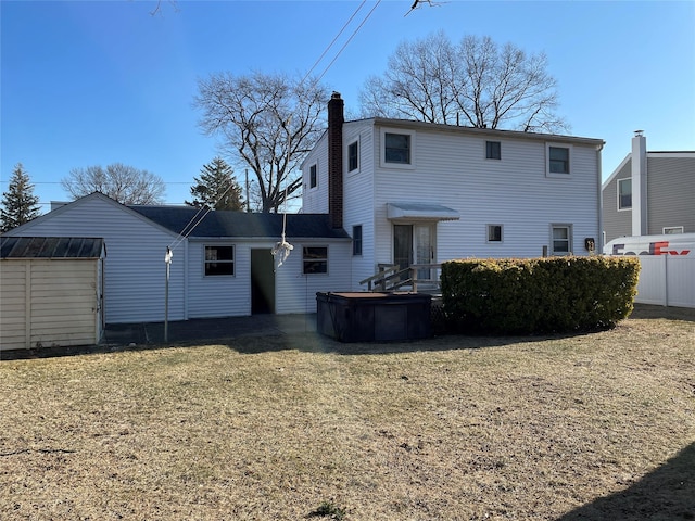 back of property featuring an outbuilding, a lawn, a chimney, and a storage shed