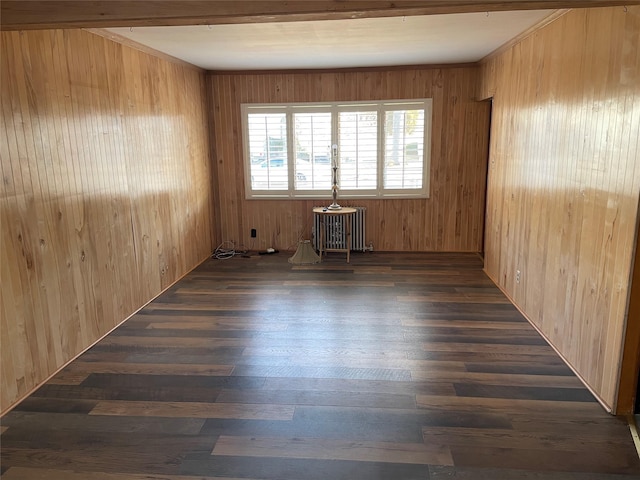 spare room with dark wood-style flooring, radiator heating unit, and wooden walls