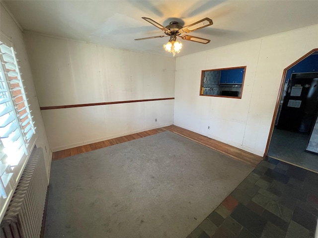 empty room with plenty of natural light, ceiling fan, and wood finished floors