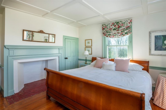 bedroom featuring coffered ceiling, a fireplace, and wood-type flooring