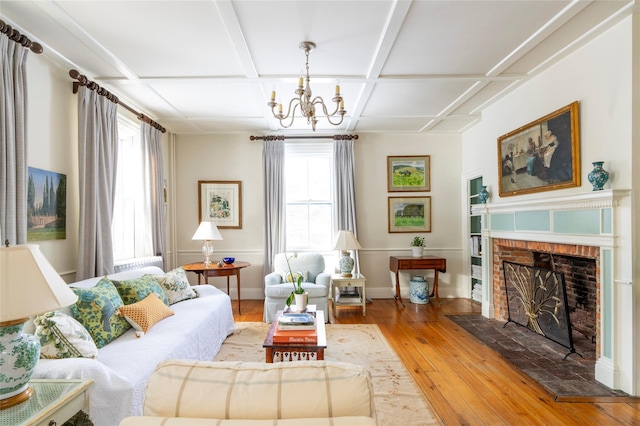 living room featuring a brick fireplace, a chandelier, wood-type flooring, and coffered ceiling