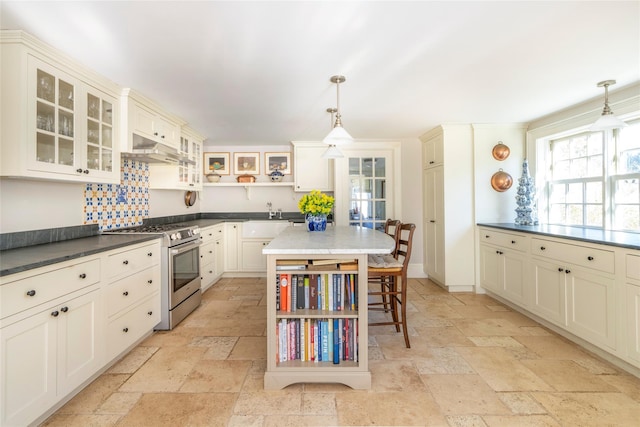 kitchen with a kitchen island, stainless steel range with gas stovetop, and pendant lighting