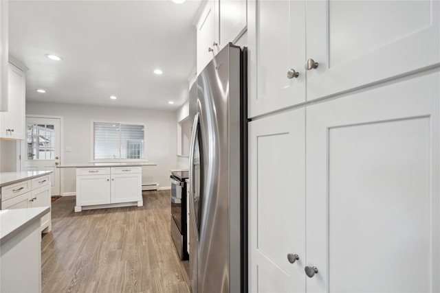 kitchen featuring a baseboard heating unit, appliances with stainless steel finishes, white cabinets, and light hardwood / wood-style floors