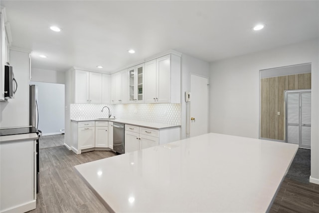 kitchen with white cabinetry, sink, dark wood-type flooring, appliances with stainless steel finishes, and decorative backsplash