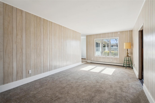 carpeted empty room with baseboard heating and wood walls