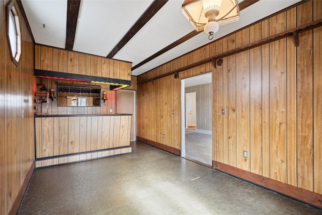 empty room featuring beam ceiling and wood walls