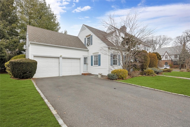 view of front of home with a shingled roof, a chimney, aphalt driveway, an attached garage, and a front yard