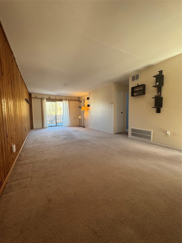 unfurnished living room featuring carpet and wood walls