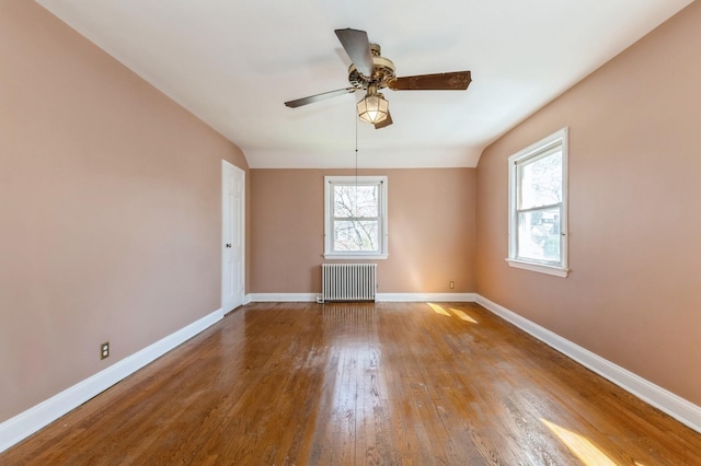 spare room featuring radiator heating unit, wood finished floors, baseboards, and ceiling fan