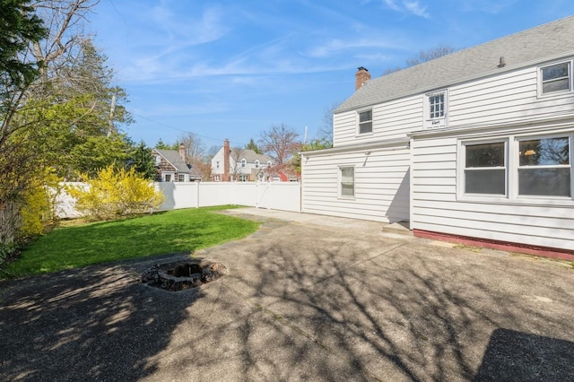 back of property featuring a fire pit, a chimney, fence, a yard, and a patio