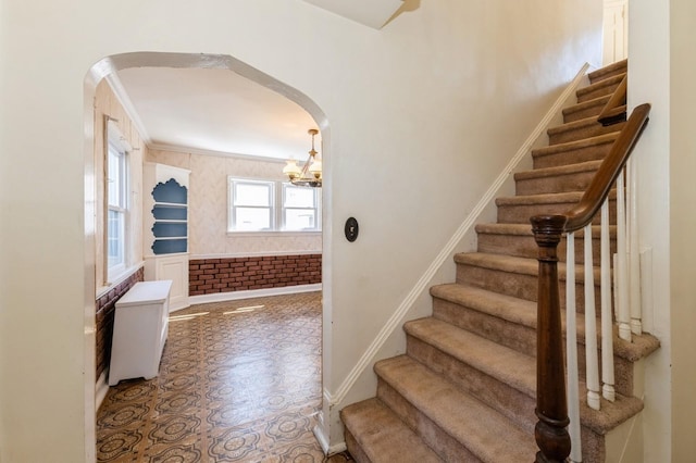 staircase with baseboards, arched walkways, and a notable chandelier