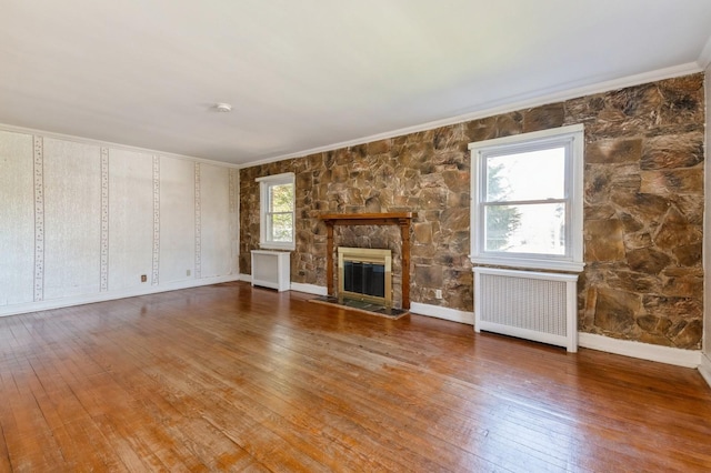 unfurnished living room featuring radiator, crown molding, and hardwood / wood-style floors