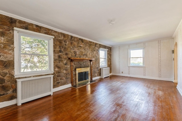 unfurnished living room with hardwood / wood-style flooring, radiator, crown molding, and a fireplace