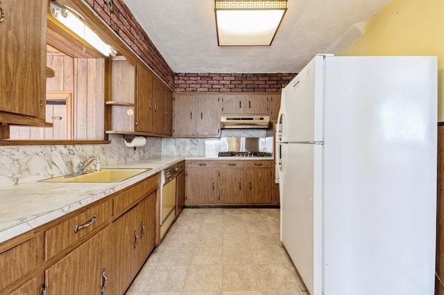 kitchen featuring under cabinet range hood, backsplash, dishwasher, a sink, and freestanding refrigerator