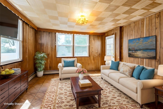 living area featuring a baseboard heating unit, wooden walls, light tile patterned flooring, and an inviting chandelier