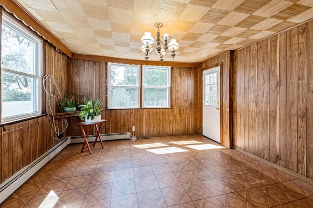 spare room with an inviting chandelier, wooden walls, and plenty of natural light