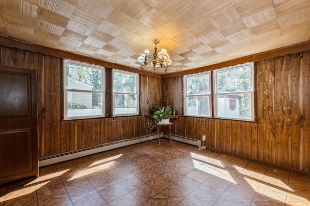 empty room featuring wooden walls, baseboard heating, and a notable chandelier